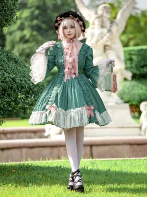 Green Rococo sweet lolita dress front view with blonde model wearing matching bonnet, featuring pink bows, ivory lace collar and cuffs, outdoor garden statue background