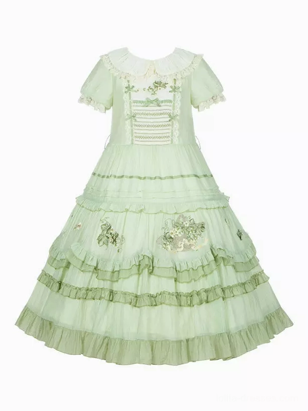 Flat-lay overhead view of green sweet lolita dress showing complete ensemble components including dress, matching sash, bonnet headwear, boutonniere, and coordinating accessories layout