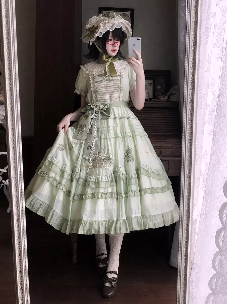 Mirror selfie full-body view of green sweet lolita dress showing lace bonnet headwear, Mary Jane shoes, voluminous ruffled skirt, indoor bedroom setting with model in dark hair