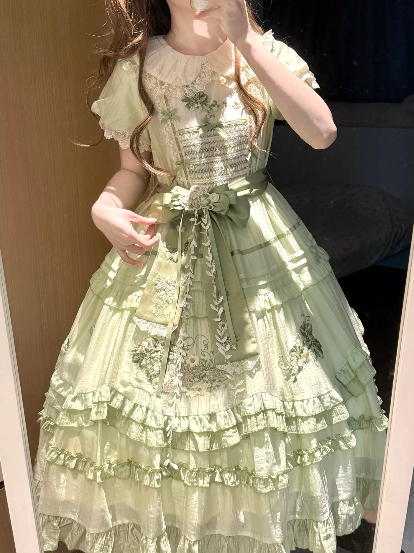 Medium close-up front view of green sweet lolita dress featuring Peter Pan collar with delicate lace trim, floral embroidery details on bodice, puffed short sleeves, and decorative waist sash bow