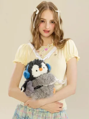 kawaii penguin plush grey crossbody bag worn by female model front view with blue earmuffs and white shoulder strap lolita accessory