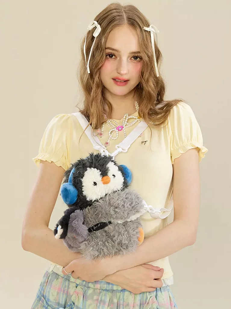 kawaii penguin plush grey crossbody bag worn by female model front view with blue earmuffs and white shoulder strap lolita accessory