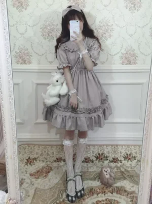 Grey Sweet Lolita OP dress with ruffled Peter Pan collar worn by model in side view, showcasing short puff sleeves and layered ruffled skirt with hair bow accessory in vintage floral room setting