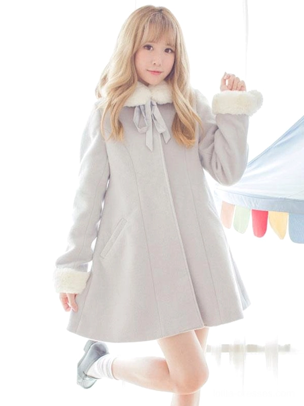 Front full-body view of grey wool sweet lolita overcoat with white fuzzy collar and pom pom trim, featuring blonde model in playful pose showcasing the elegant A-line silhouette and doll-like proportions characteristic of lolita fashion