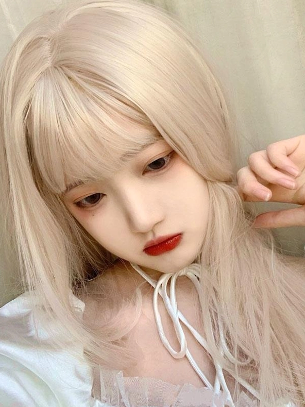 Close-up detailed shot of ash blonde heat-resistant synthetic Lolita wig showing blunt bangs and smooth hair texture with hand styling