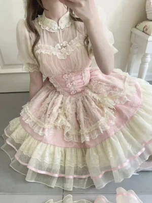 Close-up front view of pink Hime Lolita jumper dress showing lace-trimmed bodice, stand collar, tiered skirt with ribbon detailing, and ornamental embellishments