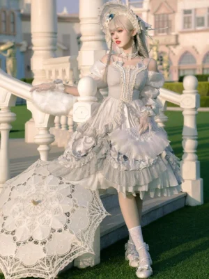 Hime Lolita dress side profile view blonde model wearing light gray floral one-piece with layered ruffled skirt and white hand fan outdoor setting