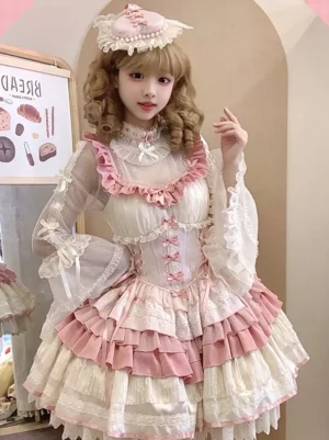 Hime Sweet Lolita jumper dress sleeveless full-body front view cream-pink color with ruffled trims lace details and bow embellishments worn by model in indoor bakery-themed setting