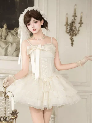 Ivory sleeveless corset Lolita mini dress with tiered tulle skirt and front bow, worn by model in European retro setting, showing lace-up bodice and fairy tale aesthetic