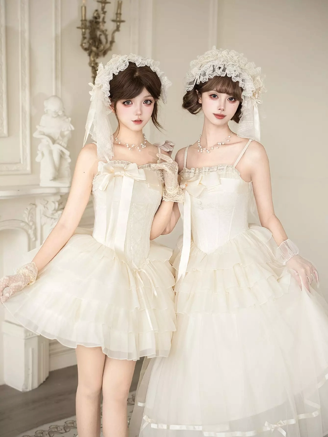 Two models wearing ivory Lolita dresses in mini and long tutu styles with matching lace hair accessories, demonstrating spaghetti straps lace-up bodice and tiered tulle silhouettes side by side