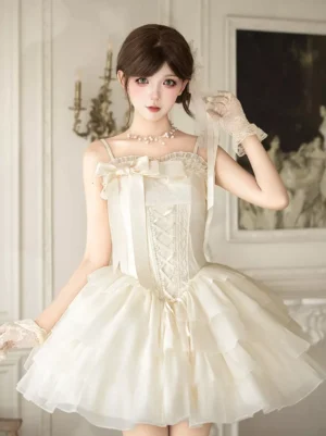 Full front view of ivory spaghetti strap corset Lolita mini dress featuring dramatic tiered ruffled tulle skirt and oversized front bow in vintage European room