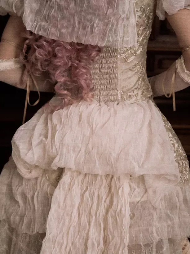 Close-up back view of ivory lolita dress showing shirred corset back and ruffled tiered lace construction details
