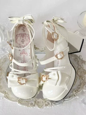 Ivory sweet lolita pumps with front bow and heart buckle ankle strap displayed on ornate vintage tray with patent leather finish chunky heel