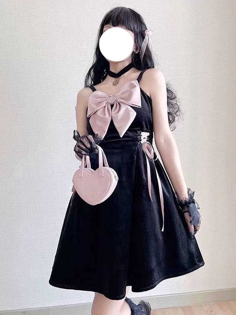 Black Jirai Kei gothic lolita slip dress with large pink chest bow, side lace-up ribbons, and heart-shaped handbag accessory, three-quarter front view