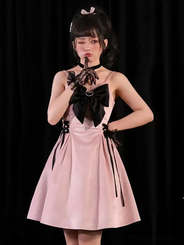 Pink Jirai Kei gothic lolita dress with large black chest bow, cross halter neckline, and side lace-up ribbon details, three-quarter front view
