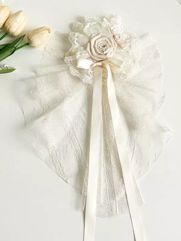 Lace bow hair accessory top-down flat lay cream lace fabric roses long satin ribbons hair bonnet detail