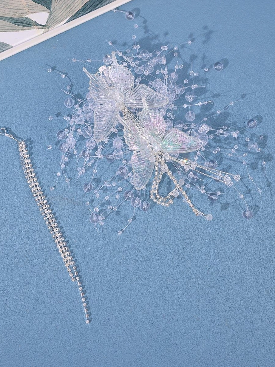 Large butterfly hair clip flat lay top view on blue background featuring double butterfly framework crystal beaded details and separate rhinestone tassel