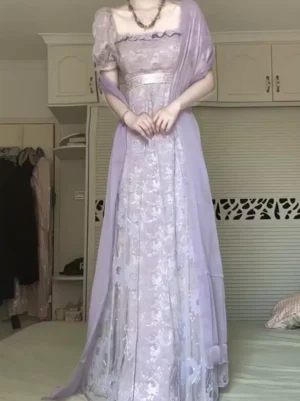 Lavender sweet lolita dress full front standing view with sheer purple shawl, empire waist design, square ruffle neckline, puff short sleeves, floral mesh fabric, and silver waist belt accent on bedroom background