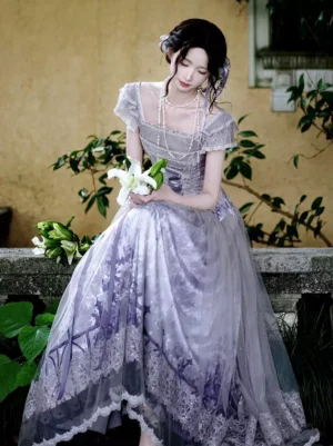 Full front view of lavender sweet lolita fairy dress on model seated in garden setting with square ruffled sleeves and printed tulle skirt