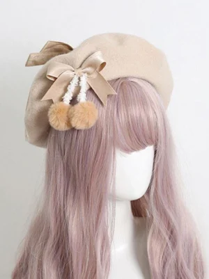 Light apricot lolita beret hat with dual satin bows and fluffy white pom-poms, front three-quarter view on mannequin