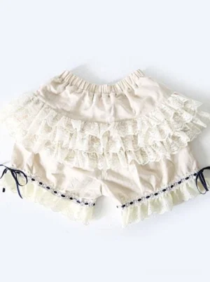 Light apricot lolita bloomer shorts with multi-layered cream lace ruffles and navy ribbon trim, flat lay top-down view showing full shorts design
