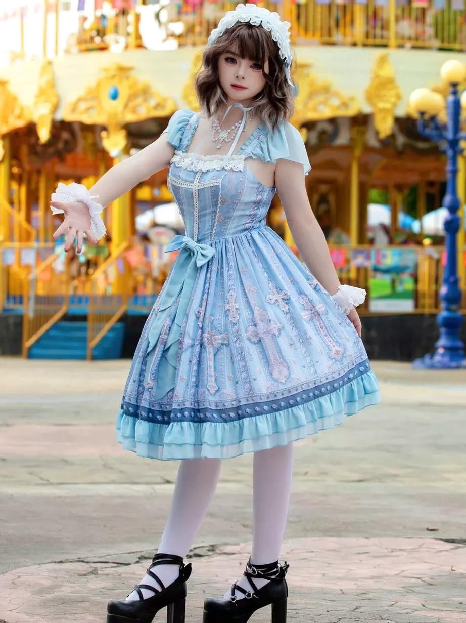 Light blue lolita dress three-quarter front view displaying cross pattern print across skirt, ruffled hem, short cap sleeves with lace trim, and structured silhouette against amusement park setting