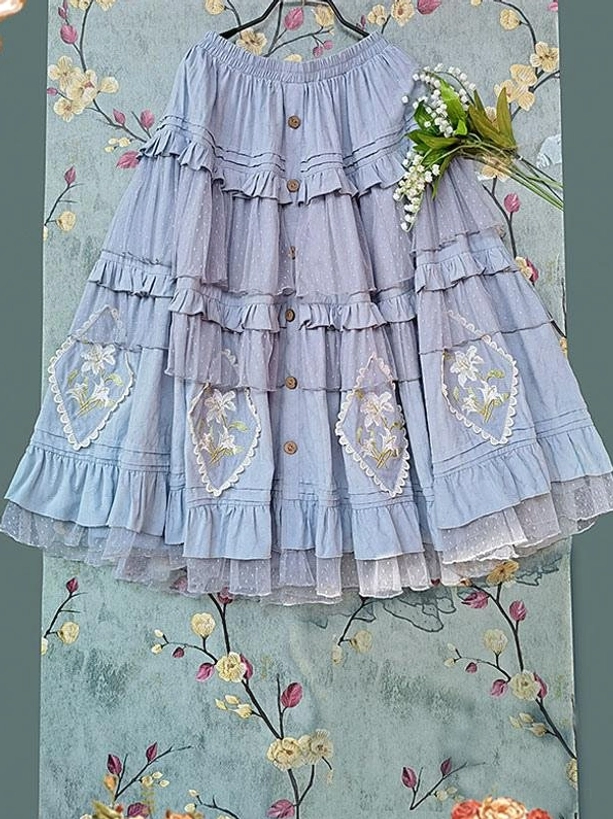 Light blue tiered Classic Lolita dress flat lay hanging view with front button details heart-shaped floral embroidery and layered ruffled tulle hem