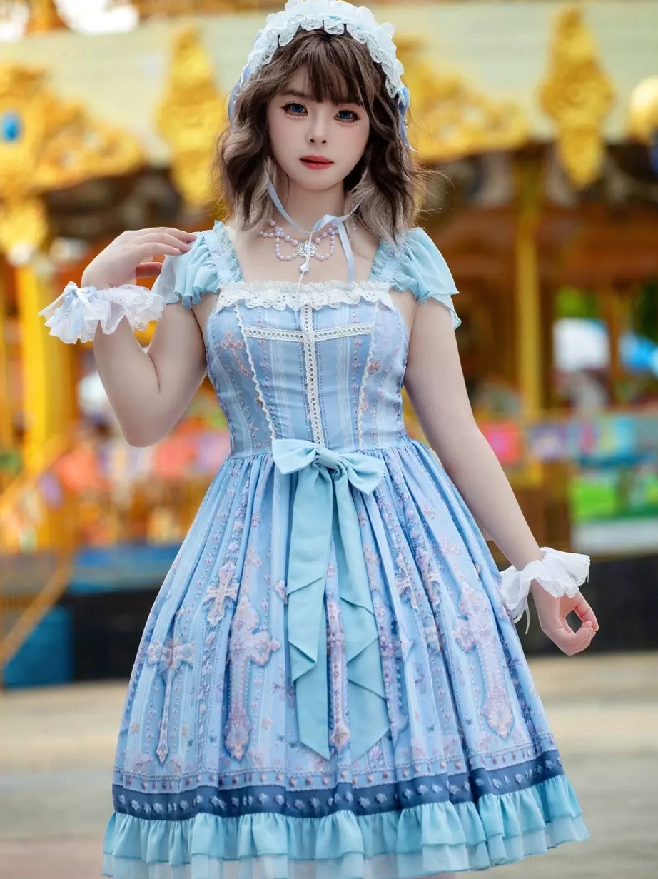Light blue lolita JSK dress three-quarter front view with ruffled sleeve cuffs, front waist bow, cross patterned skirt, square neckline, and lace trim against carousel amusement park backdrop