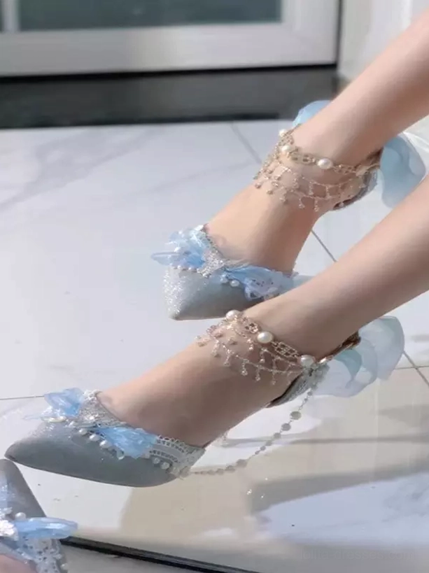 Light blue glitter Lolita stiletto shoe with blue bow and pearl ankle chain in bright indoor setting, side close-up