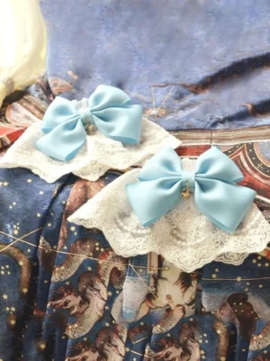 light blue sweet lolita bow accessories pair with white lace underlays and gold star charms displayed on vintage star print fabric flat lay close-up