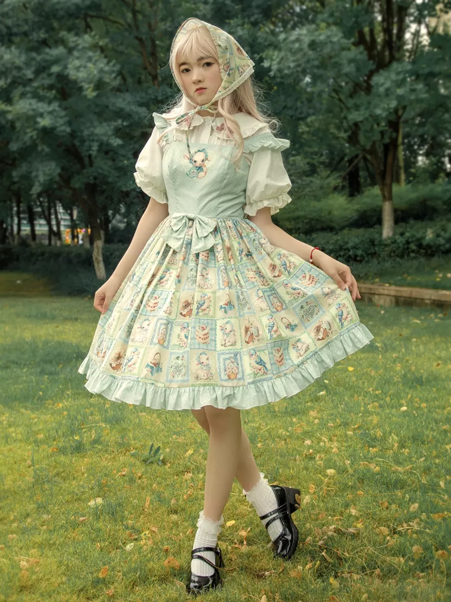 Full body front shot of sheep bird cake print sweet lolita jumper dress with light blue bodice, flared printed skirt, matching headscarf, and black Mary Jane shoes on outdoor lawn