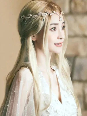 Light gold rococo lolita wig with crystal leaf forehead crown worn by model, right three-quarter profile view showing straight blonde hair and ornate tiara details against stone wall background