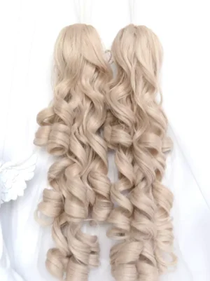 Back view flat lay of light gold detachable twin spiral curly ponytail wig extensions with angel ornament accessory, heat-resistant fiber lolita wig components on white fabric background