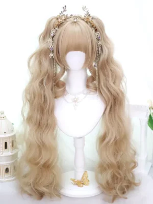 Light gold twin tails lolita wig front three-quarter view with blunt bangs and wavy hair texture displayed on mannequin head with ornate castle studio backdrop and gold tassel hair accessory