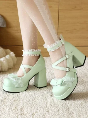 Light green Sweet Lolita chunky heel pumps worn with polka-dot sheer socks, showing side rear angle with heart buckle cross straps, ruffled ankle trim and front bow frill decoration