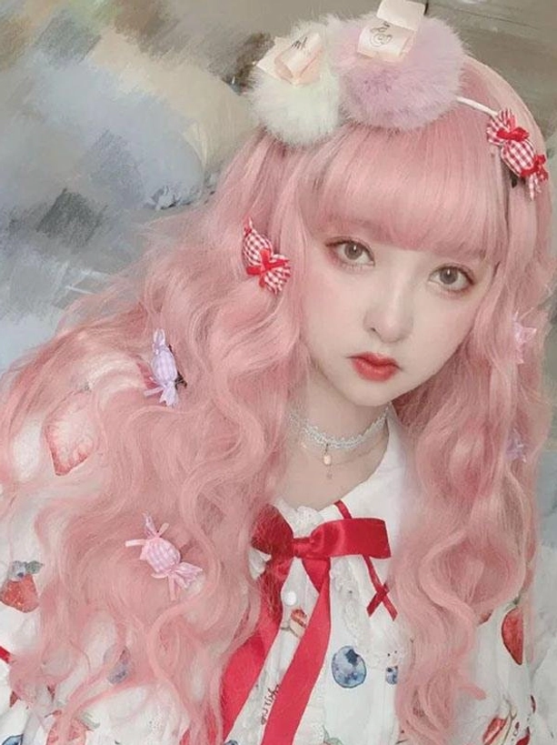 Three-quarter view of light pink wavy lolita wig with candy-shaped hairpins styled with fruit printed sweet lolita dress
