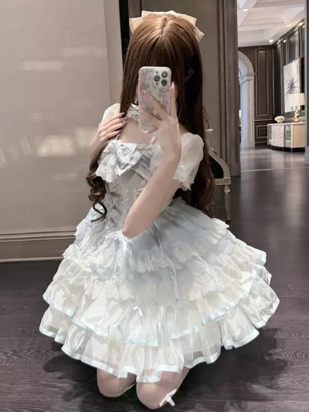 Light sky blue lolita dress side back three-quarter kneeling view displaying puffy tiered ruffle skirt construction and satin fabric sheen
