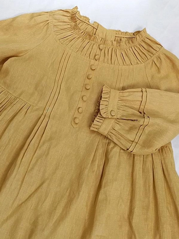 Mustard yellow linen lolita dress flat lay showing shirred frilled neckline, fabric-covered front buttons, ruffled buttoned cuffs, and linen woven texture details