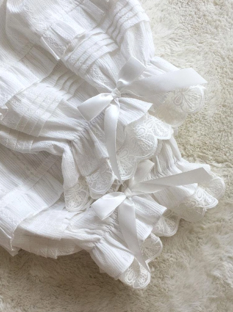 Lolita bloomers cuff close-up flat lay showing multiple satin bows, layered lace ruffles, and textured cotton jacquard fabric with precious embellishment details