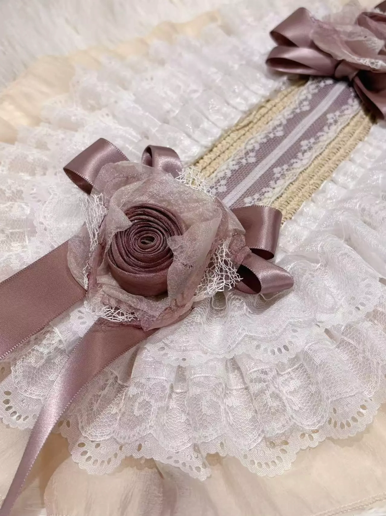 Close-up detail view of lolita bonnet headdress featuring mesh-overlay fabric flower ornament, woven hat band structure, delicate ruffled lace trim, and intricate embellishment craftsmanship