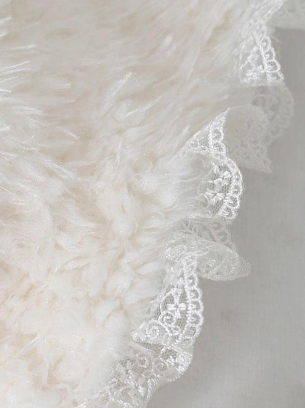 Close-up macro photography of embroidered white lace trim on bonnet showing intricate detailing and fluffy off-white fabric texture