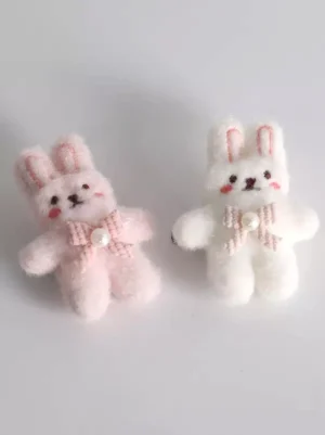 Flat lay front view of pink and white plush bunny ear hair clips set featuring embroidered blush details, gingham bow decoration with pearls, and cute kawaii design elements for lolita accessories