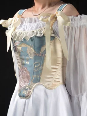 Lolita corset bustier three-quarter angle showing decorative bow straps satin side panels and embroidered floral jacquard on model