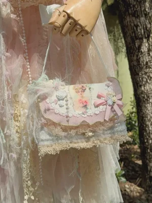 Side profile of pastoral lolita crossbody bag showcasing pearl accents and lace tassel hem, styled with pink lolita dress on wooden mannequin, displaying intricate ruffled edge detailing and romantic aesthetic