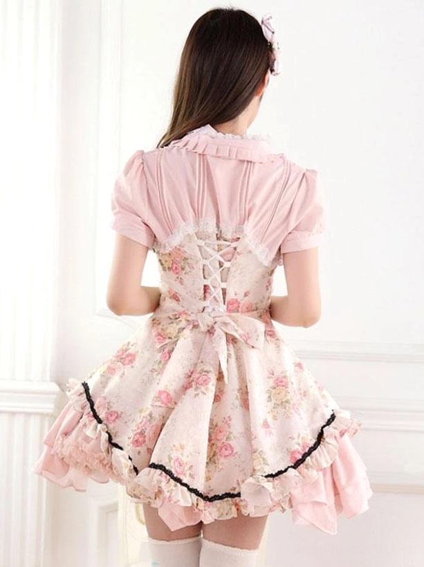 Pink lolita one-piece dress back view showcasing corset-style lace-up closure with decorative bow accent, ruffled hem trim detail, floral printed skirt fabric, rear silhouette architecture