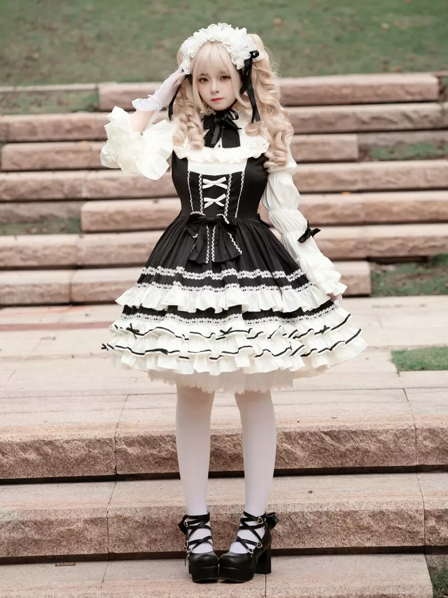 Gothic lolita dress front view with model showing flared ruffled cuffs, bow decorations, and dramatic black and white color contrast