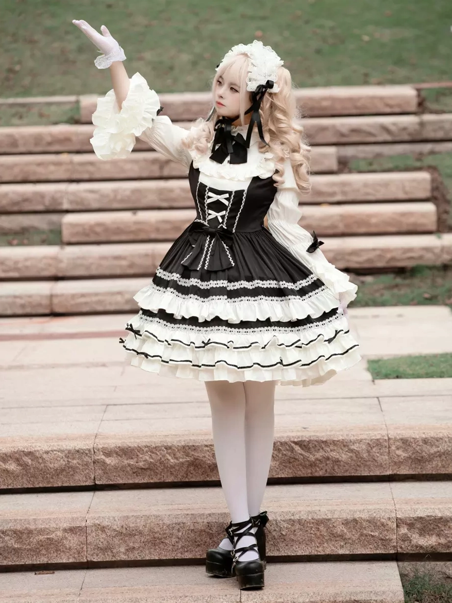 Gothic lolita dress low angle front view with model wearing white lace gloves, black platform shoes, and voluminous ruffled skirt silhouette