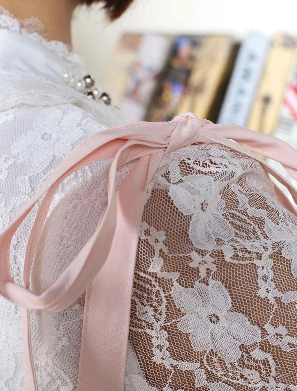 Close-up detail shot of pink satin suspender strap with pearl trim and floral lace fabric embellishment