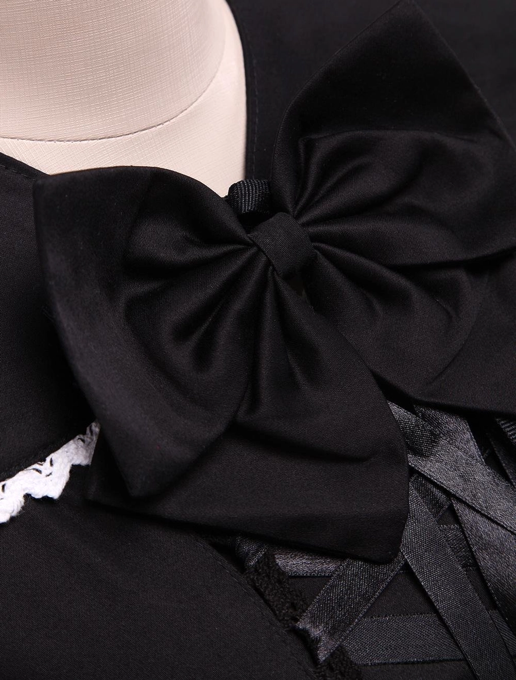 Close-up of black Lolita dress collar and bodice detail featuring large satin bow accent, white lace trim, and front ribbon lace-up