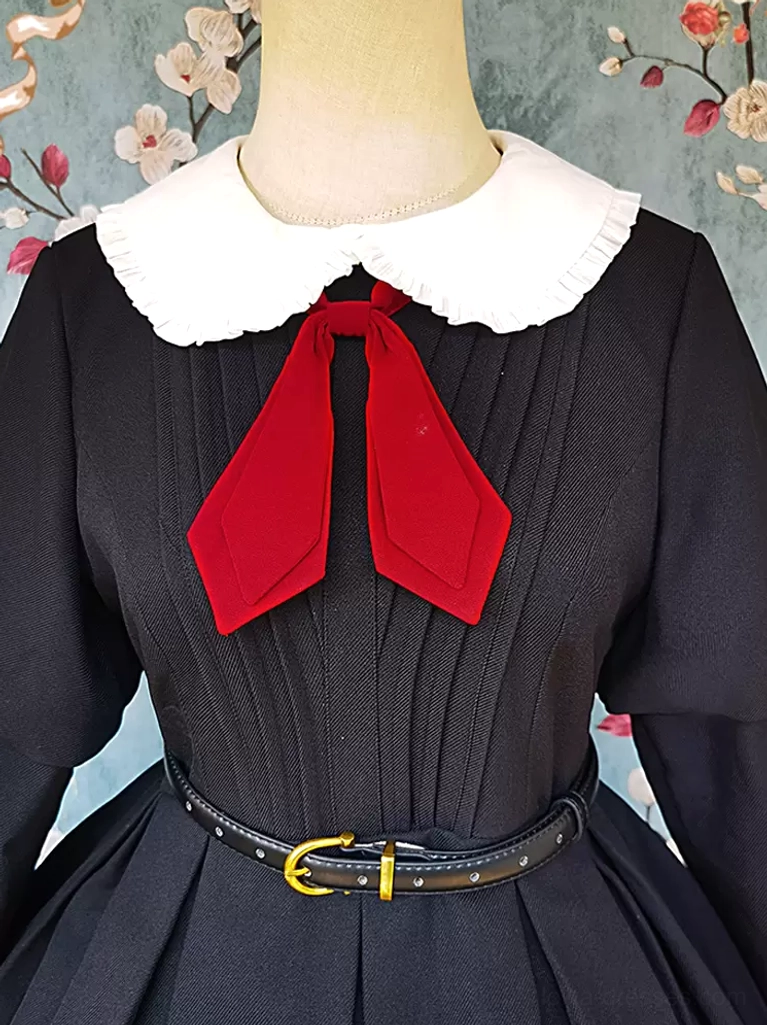 Close-up detail of classic lolita dress showing pleated bodice construction, white Peter Pan collar, red bow accent, and gold buckle belt hardware